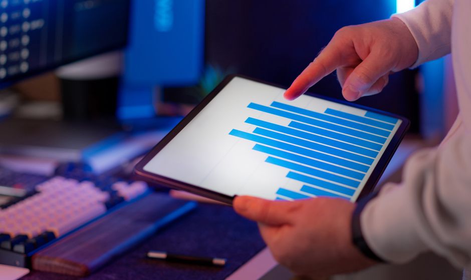 Business professional analyzing bar chart on tablet in office setting, highlighting data insights