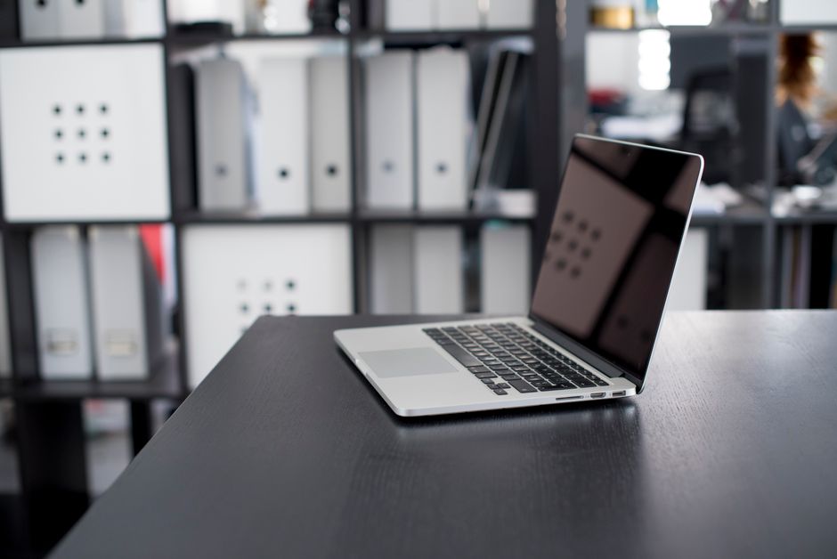 MacBook Pro displayed on a minimalist office desk with shelves in the background
