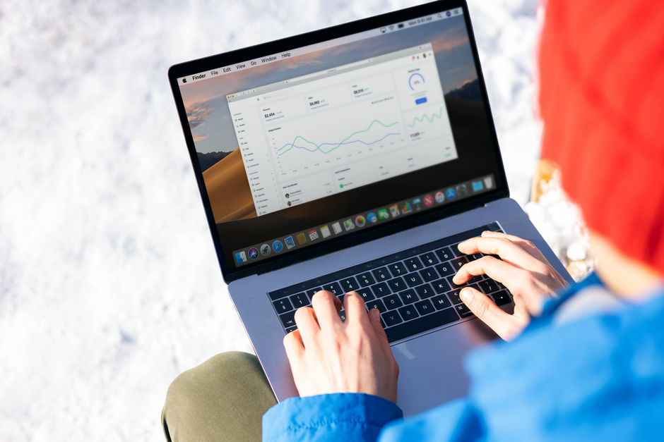 A person in a blue jacket analyzing business analytics on a laptop outdoors during winter