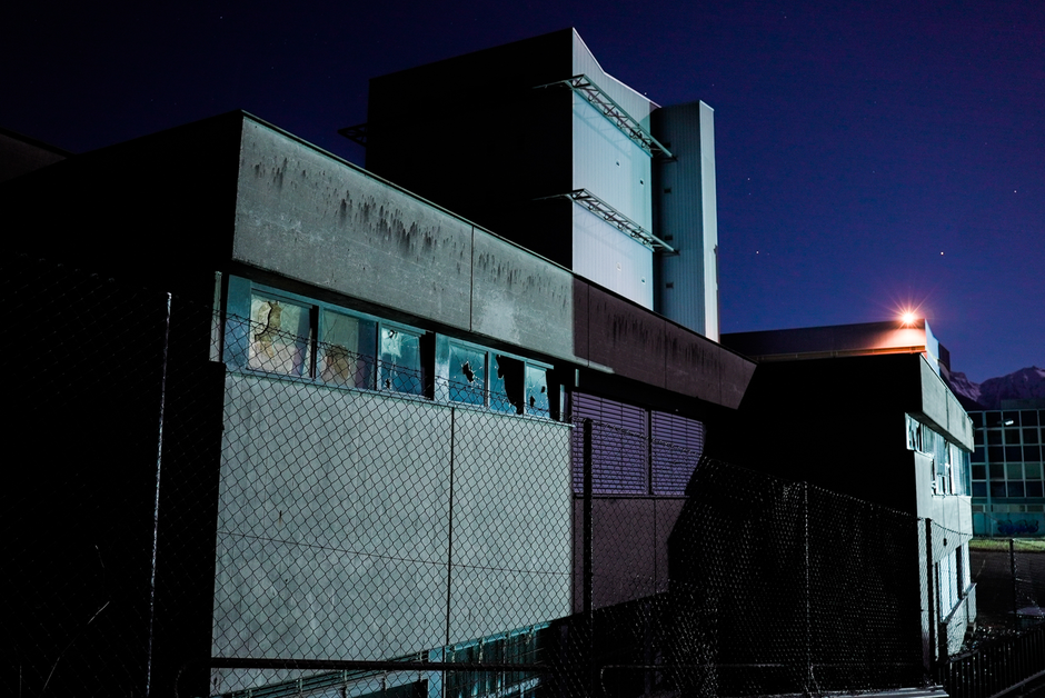 A dark view of an abandoned factory at night, showcasing broken windows and eerie atmosphere
