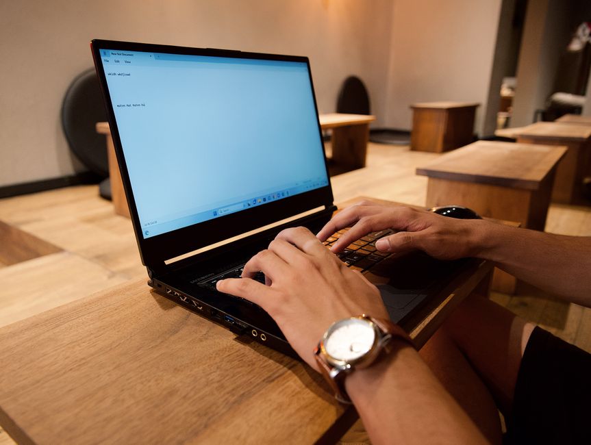 A person working on a laptop in a modern office setting, focused on typing