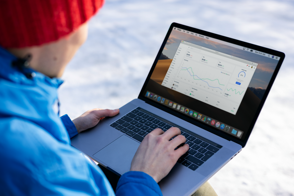 Person working on a laptop analyzing charts in an outdoor setting during winter