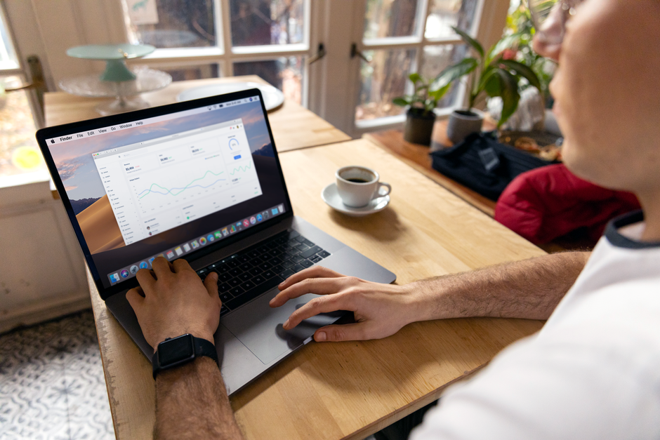 A person working on a laptop with business analytics displayed, showcasing a remote work setup in a cozy environment