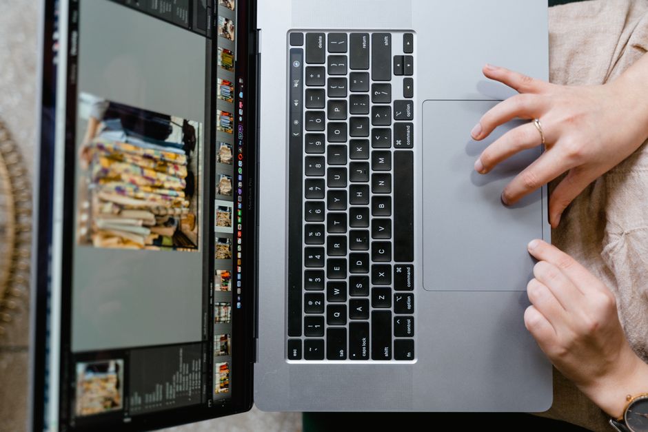 Close-up of hands using a laptop for photo editing, showcasing creativity in digital media