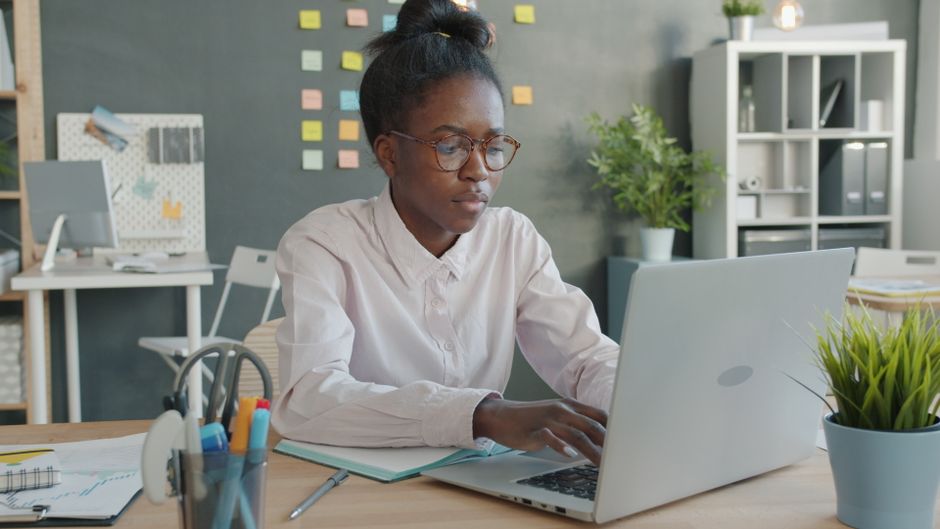Focused young woman working on her laptop in a modern office setting