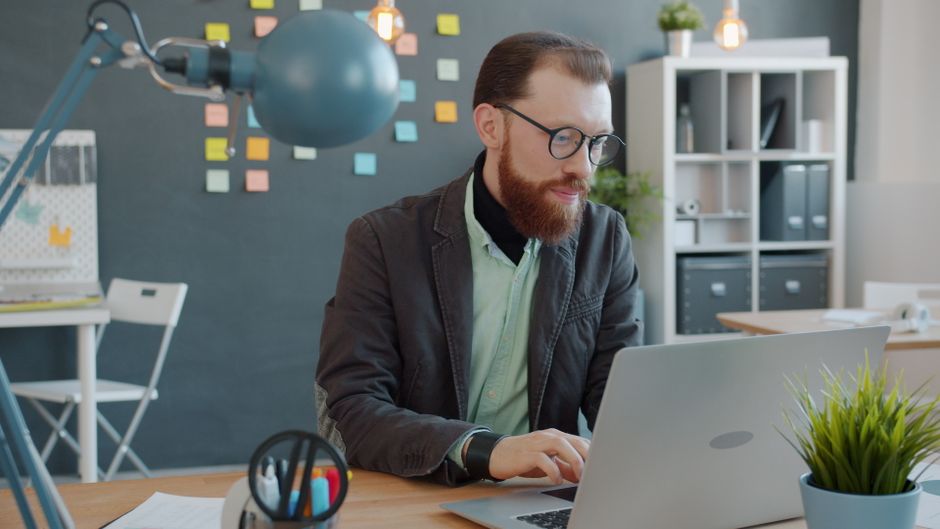 Businessman focuses on laptop in trendy office space with notes