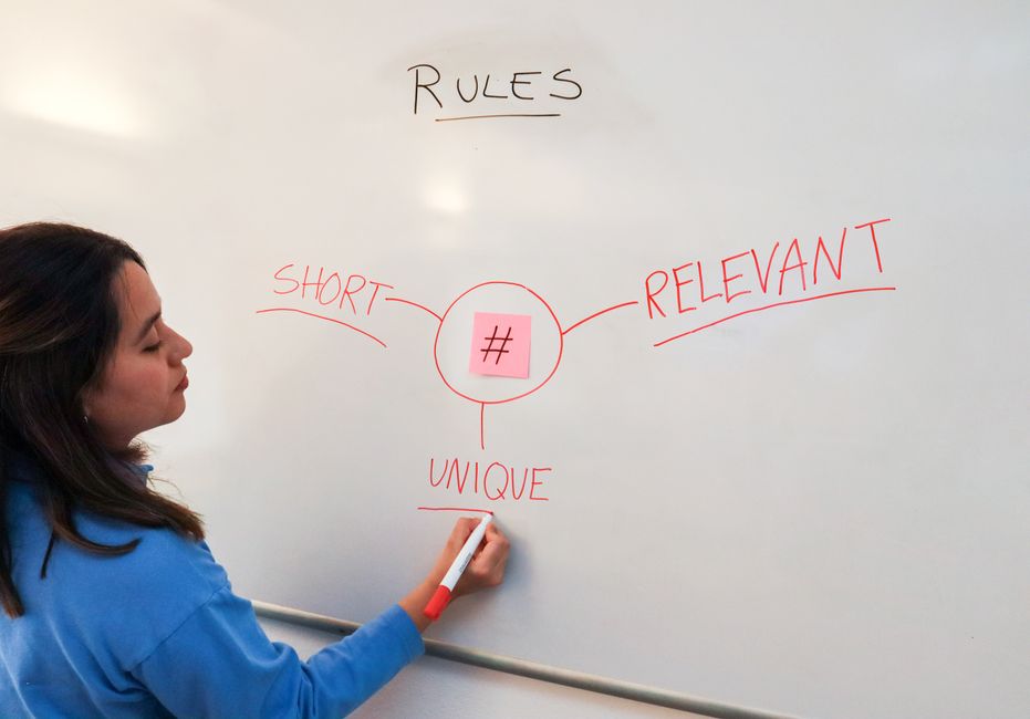Woman illustrating marketing rules with hashtags on a whiteboard for effective branding strategies