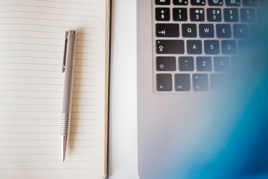 Simple workspace setup featuring a laptop keyboard and a notebook with a pen