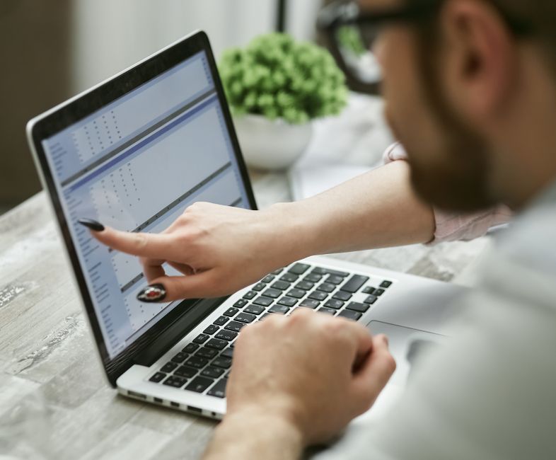 Two people working on a laptop analyzing data, pointing at screen