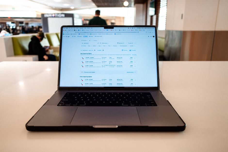A modern laptop displaying flight schedules on a white table in an airport lounge